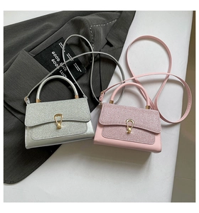 Detail of silver and pink glitter panel handbags with gold horseshoe buckles on grey fabric