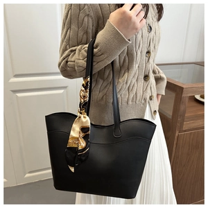 Detail of black wave-edge tote bag with decorative silk scarf on a stylish woman
