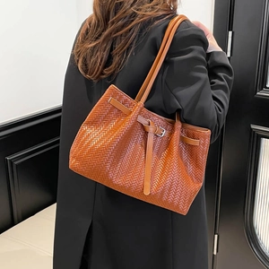 Caramel brown woven leather tote bag shown with professional black suit for office style