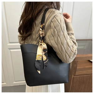 Detail of black matte leather tote bag with printed silk scarf on shoulder strap