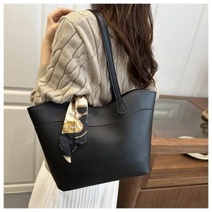 Detail of black leather tote bag with stylish patterned silk scarf on model's shoulder