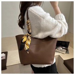 Detail of dark brown matte leather tote bag with silk scarf on handle for office work
