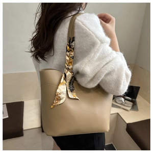 Detail of minimalist beige tote bag featuring a decorative black and yellow printed silk scarf