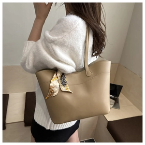 Detail of a beige tote bag with a silk scarf handle accessory shown in a cafe setting