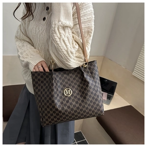 Détail du grand sac cabas avec monogramme M marron foncé et emblème doré du logo