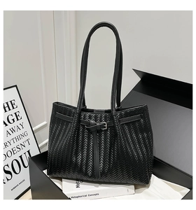 Dettaglio ravvicinato della borsa shopper nera intrecciata con fibbia metallica