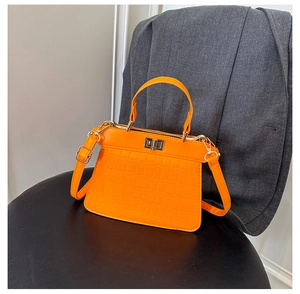 Detail einer hellorangen Kelly-Handtasche mit Krokostruktur und goldenem Drehverschluss