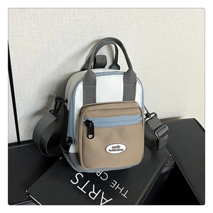 Detail of multi-functional crossbody bag featuring patchwork fabric and zip pocket