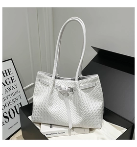 Dettaglio borsa tote bianca intrecciata con fibbia argentata in una confezione regalo chic