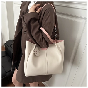 Detail of soft cream tote bag featuring pink LEATHER patch and cute kitten charm