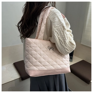 Detail of pink quilted tote bag featuring a metallic bow and soft padded texture
