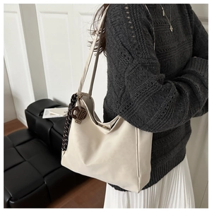 Detail of off-white tote bag featuring a checkered silk scarf and vintage metal charms