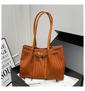 Dettaglio della borsa tote intrecciata color caramello con fibbia metallica e nodi in pelle