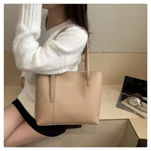 Detail of minimalist beige tote bag in PU leather showing texture and brand lettering