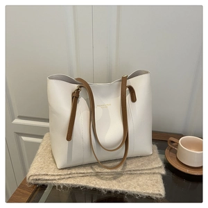 Close-up of white leather tote bag with brown straps on soft cashmere background