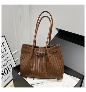 Dettaglio della trama intrecciata marrone e fibbia metallica su borsa tote trendy