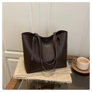 Close-up of brown leather tote bag with gold lettering and adjustable straps
