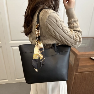 Minimalist black tote bag with silk scarf accessory shown on model in modern room
