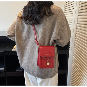 Détail d'un mini sac à bandoulière rouge avec lettrage FASHION et pendentif métallique