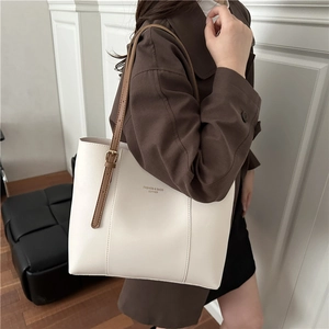 Minimalist white leather tote bag with brown straps and adjustable gold metal buckles