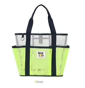 Close-up of front mesh pockets and navy handles on a green beach tote bag