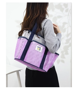 Close-up of a large purple mesh beach bag with sturdy blue straps and a brand logo patch