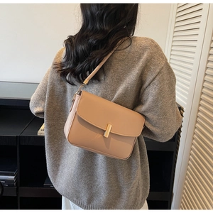 Detail of light beige leather crossbody bag with a gold cylindrical lock and slim strap