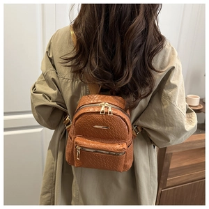 Detail of vintage woven texture on brown leather backpack with gold zippers and hardware