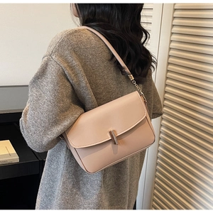 Detail view of the sleek metal clasp and chain strap on the beige crossbody bag
