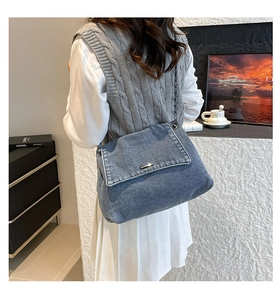 Close-up of retro denim shoulder bag with metal chain strap worn by a model in casual style