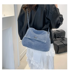 Blue denim crossbody bag with metal chain strap shown on model for a trendy look