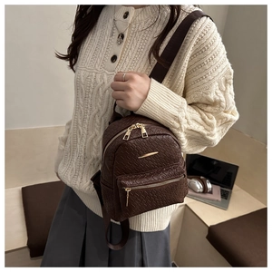 Detail of woven texture mini backpack with gold zippers and branded fabric straps