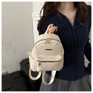 Detailed woven texture of this cream beige minimalist backpack held by a model