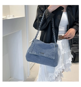 Detail of denim shoulder bag with chain strap worn by model in a chic street style