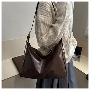 Détail du grand sac hobo marron foncé en similicuir huilé porté avec un pull beige
