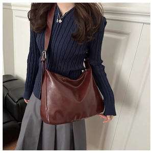 Détail d'un sac hobo bordeaux en cuir brillant avec une forme en demi-lune très spacieuse