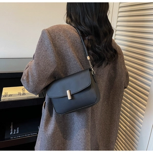 Close-up of black leather crossbody bag with a gold metal clasp and chain strap