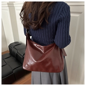 Sac fourre-tout en cuir bordeaux porté avec un pull bleu marine et une jupe grise