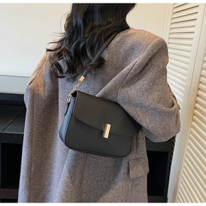 Chic black matte leather crossbody bag with gold lock buckle and chain strap on a model