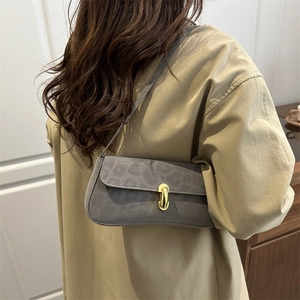 Sac sous l'aisselle gris chic avec motif léopard et fermoir doré porté à l'épaule
