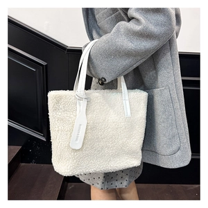 Detail of white fleece bucket bag featuring leather handles and fashion logo tag