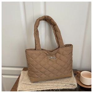 Detail of brown quilted tote bag with diamond pattern and silver metal bow ornament