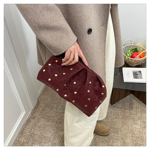 Close-up of burgundy leather clutch bag with leopard embossed pattern and golden studs