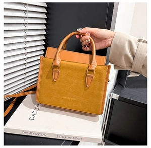 Gros plan détaillé du sac cabas jaune moutarde montrant la texture du cuir lisse et suédé