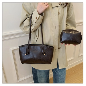 Detail of dark brown leather tote bag set with glossy finish and matching pouch