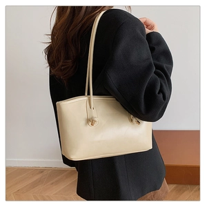 Detail of beige tote bag side showing unique knot design and gold metal cylinder hardware