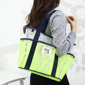 Mesh beach tote bag with neon green mesh compartments and blue handles worn by a model