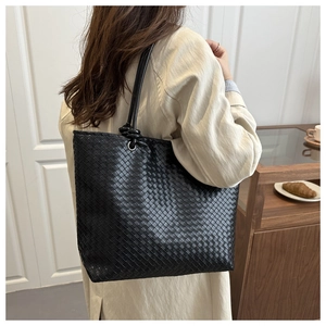 Detail of black woven leather tote bag featuring signature Intrecciato craft and slim straps