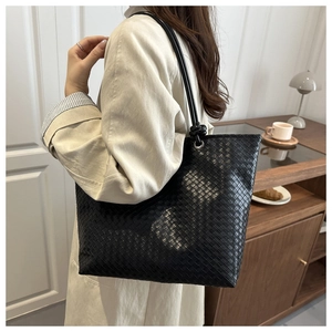Detail of black woven leather tote bag with metallic eyelets and slim shoulder strap