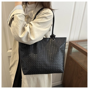 Detail of the woven texture and knot handle on a black large leather tote bag